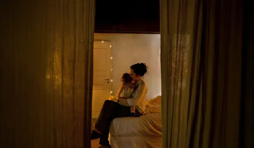 Mor som tr&oslash;ster barnet sitt i sengen uten tekst