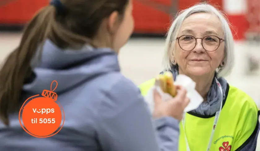 Sanitetskvinne sitter med en ungdom som spiser