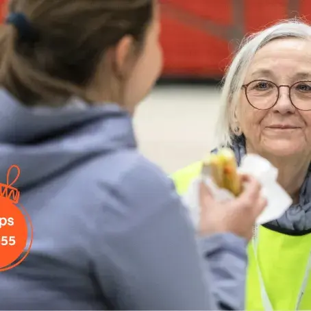 Sanitetskvinne sitter med en ungdom som spiser